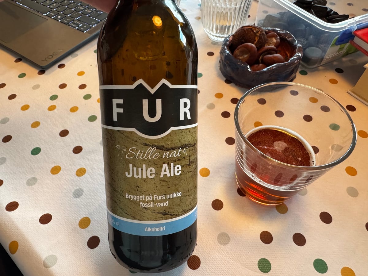 Flaske Fur Stille Nat Alkoholfri Jule Ale ved siden af et glas mørkt ravfarvet øl