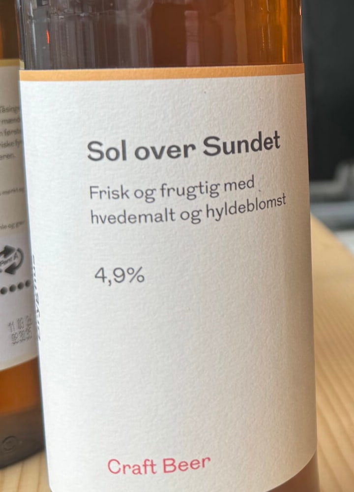 Nærbillede af frontetiketten på Sol Over Sundet med hvedemalt, hyldeblomst og 4,9 procent