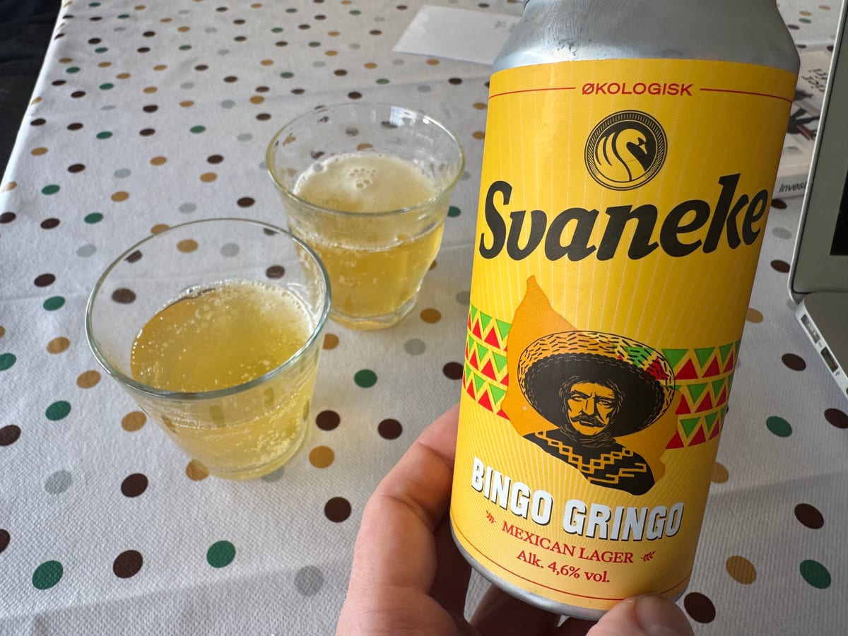 En gul dåse Svaneke Bingo Gringo holdes foran to glas med lys gylden øl